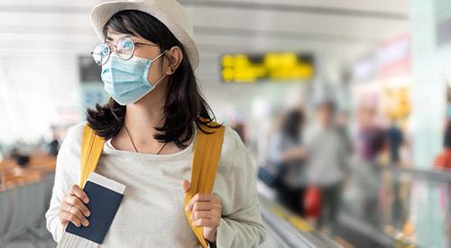 Young woman with mask and book at airport
