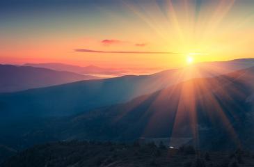 image of sun rising behind mountains