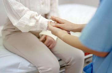 Hand of female comforting patient in consulting room