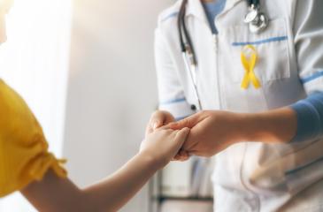 Doctor wearing yellow ribbon holding patient's hand