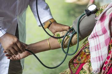 A doctor checks a patient's blood presure outside