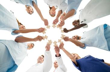 Medical Team Joining Jigsaw Pieces In Huddle stock photo