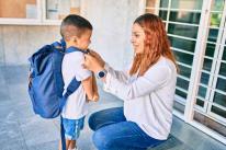 Student parent putting backpack on child
