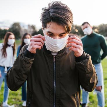 teen with face mask and three others standing in background