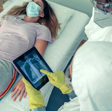 patient laying on hospital bed while doctor examines xray of heart on tablet computer