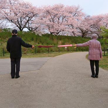couple with umbrellas standing at distance