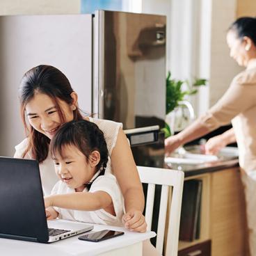 woman with child at laptop near kitchen
